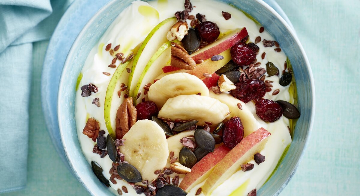 Quarkspeise mit Früchten in einer blauen Schüssel auf blauem Hintergrund.