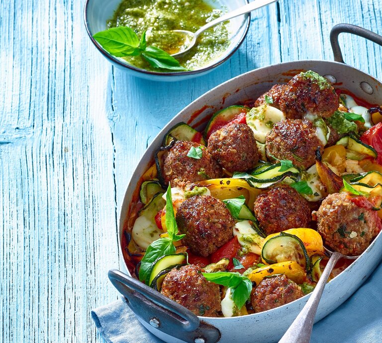 Draufsicht: ein Ratatouille-Hackbällchen-Pfanne in einer Form. Daneben eine runde Schale mit einer Sauce. | © Matthias Liebich
