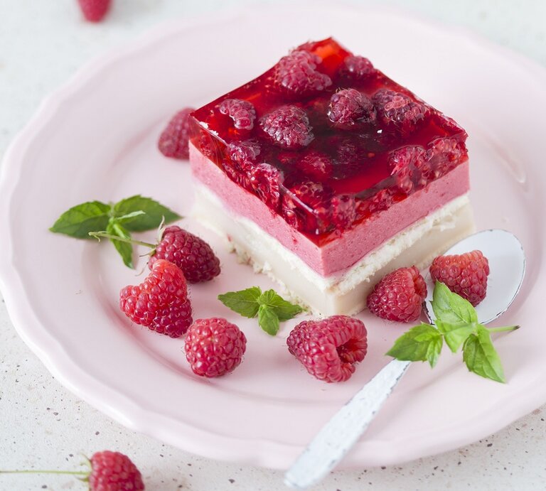 Ein Stück vom Himbeerkuchen auf einem hellen Teller weißem Untergrund. | © StockFood/Laniak, Malgorzata
