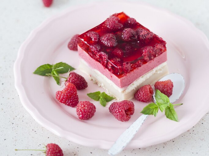 Ein Stück vom Himbeerkuchen auf einem hellen Teller weißem Untergrund. | © StockFood/Laniak, Malgorzata