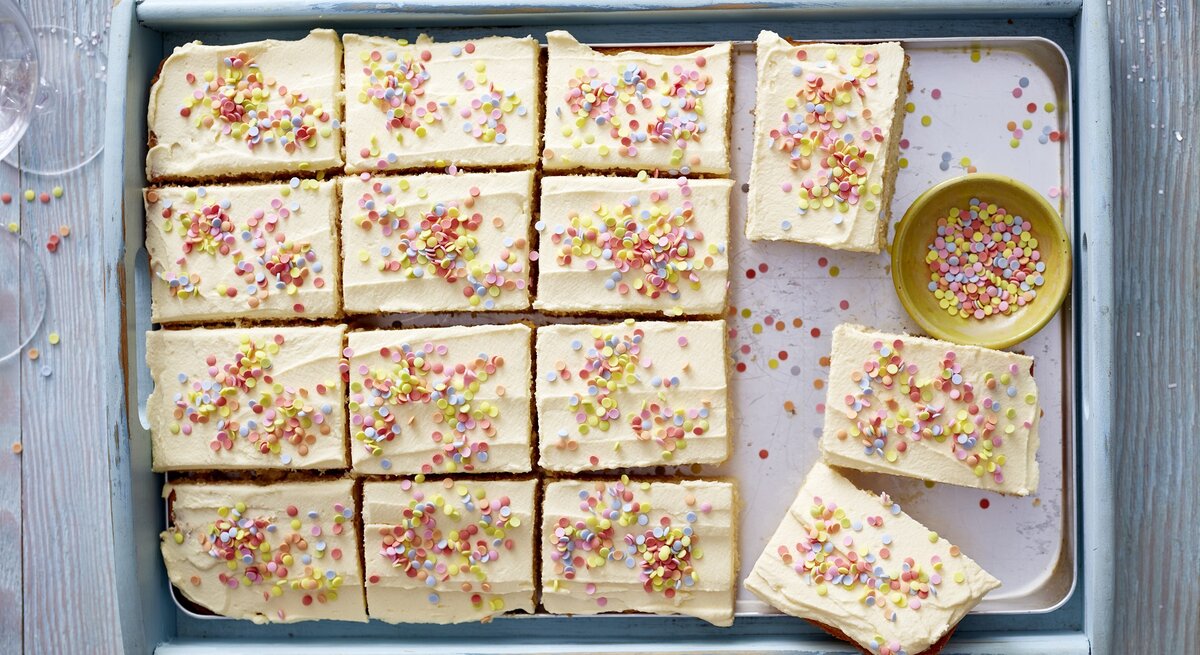 Konfetti-Kuchen auf einem Backblech auf einem hellblauen Hintergrund. Auf dem Hintergrund Konfetti verteilt. 