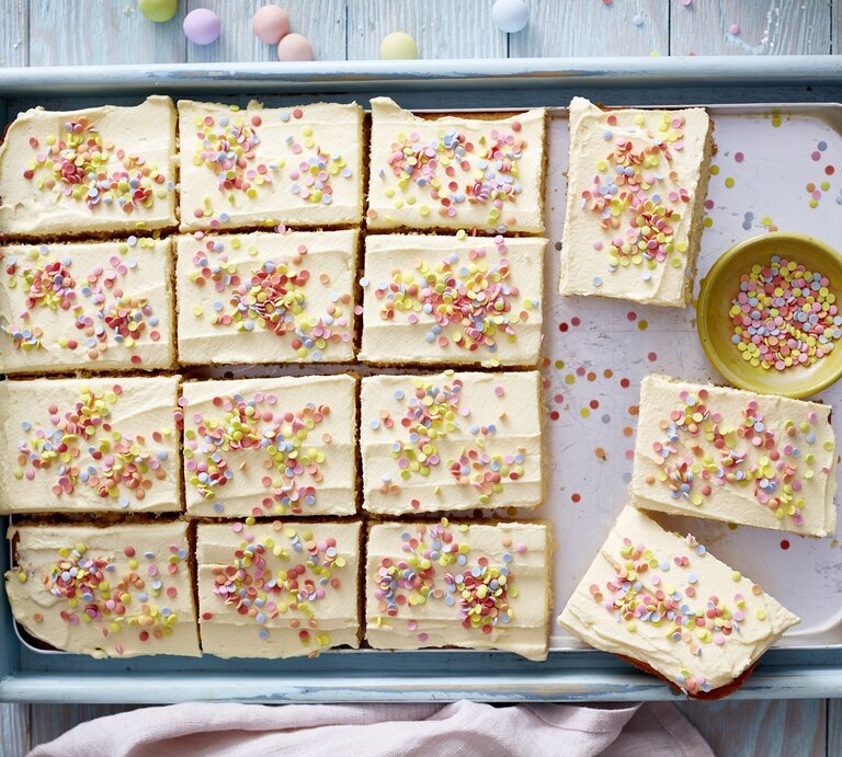 Konfetti-Kuchen auf einem Backblech auf einem hellblauen Hintergrund. Auf dem Hintergrund Konfetti verteilt.  | © Isabell Triemer