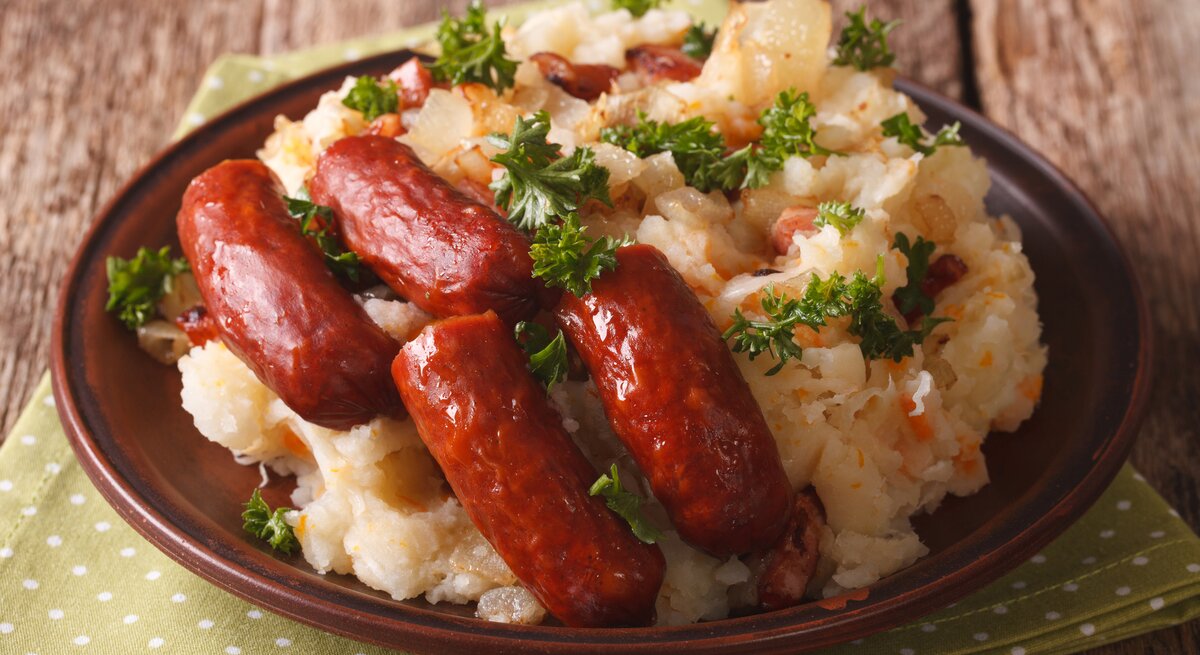 Runder Teller, darauf niederländisches Traditionsgericht Stamppot mit Sauerkraut und Wurst.