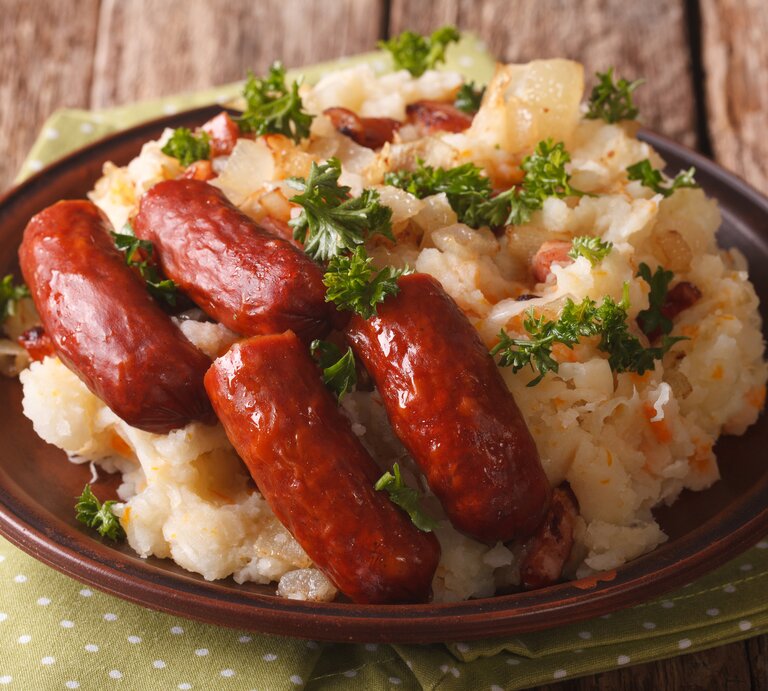 Runder Teller, darauf niederländisches Traditionsgericht Stamppot mit Sauerkraut und Wurst. | © iStock.com/ALLEKO