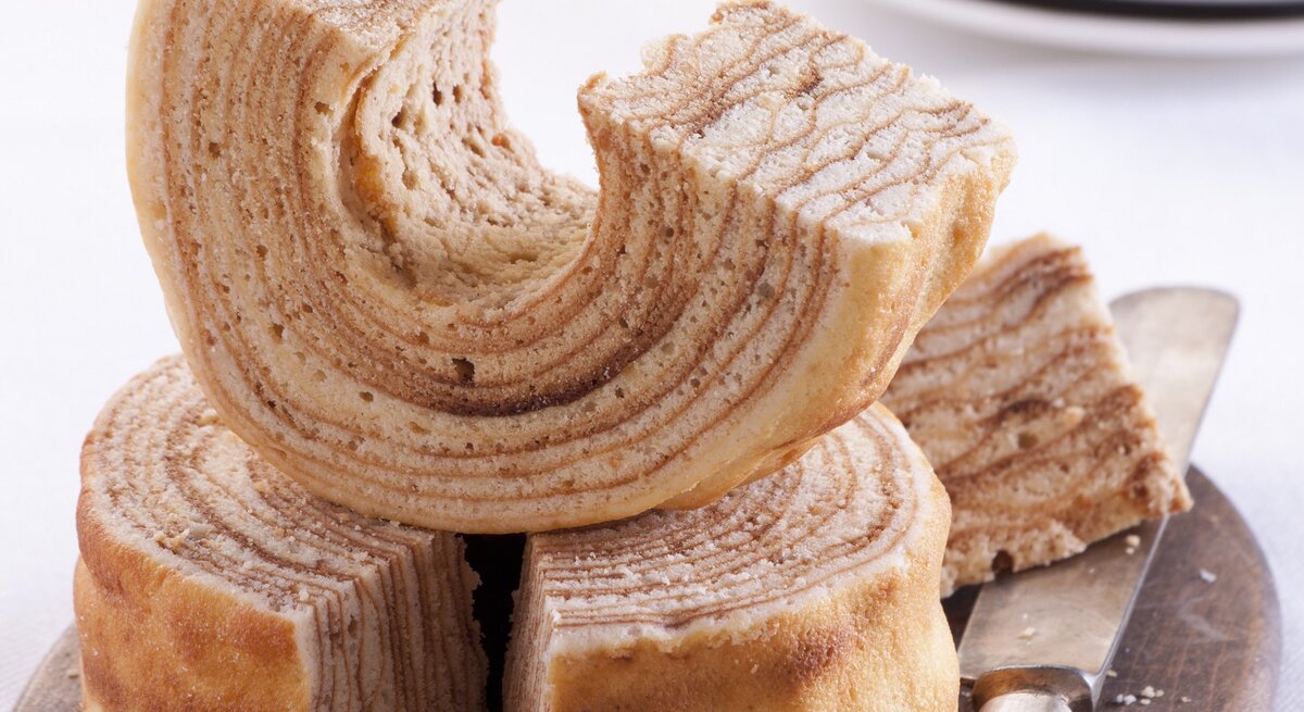 Mehrere Stücken vom Baumkuchen auf hellem Untergrund. Alles von schräg oben fotografiert.