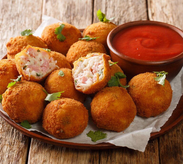 Runder Teller, darauf mehrere frittierte Schinken-Bällchen mit Sauerkraut, daneben ein tomatiger Dip.  | © iStock.com/ALLEKO