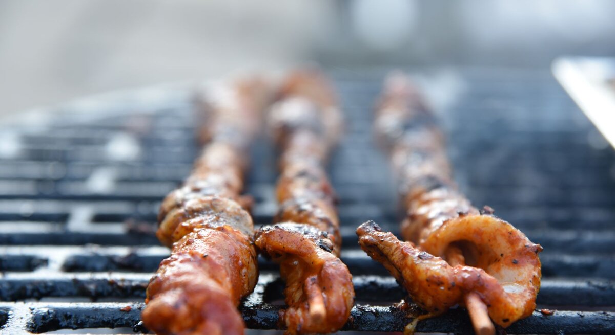 Selbst gemachte Grillfackeln mit Paprikamarinade beim Grillen auf einem Grillrost. Außenaufnahme. Frontalansicht.