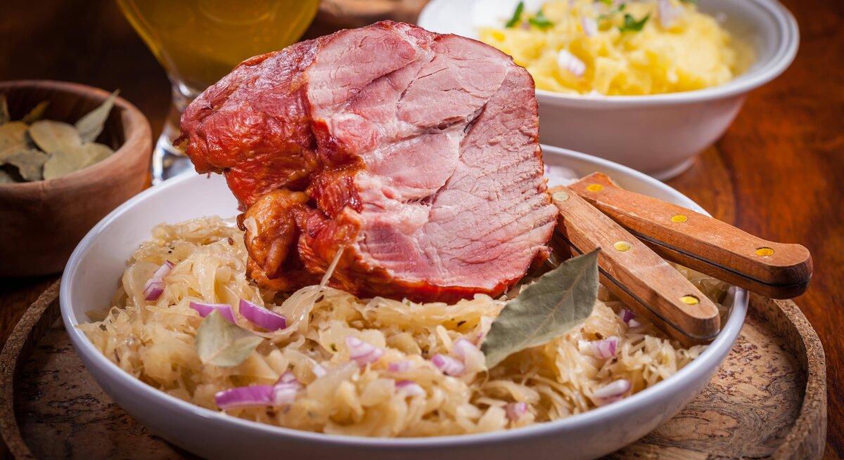 Kasslerbraten auf Sauerkrautbett auf gutbürgerlich gedecktem Tisch.
