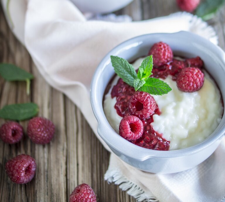Milchreis mit Himbeeren / runde Schüssel / Tuch / Untergrund Holz / Nahaufnahme/ Draufsicht | © StockFood/LieberBacken
