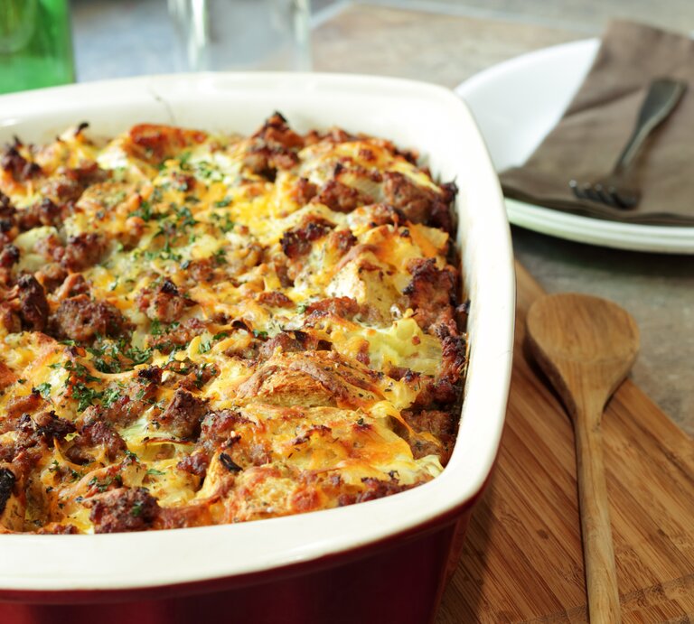 Brotauflauf mit Hackfleisch in Auflaufform auf Holzbrett. | © Getty Images/wsmahar