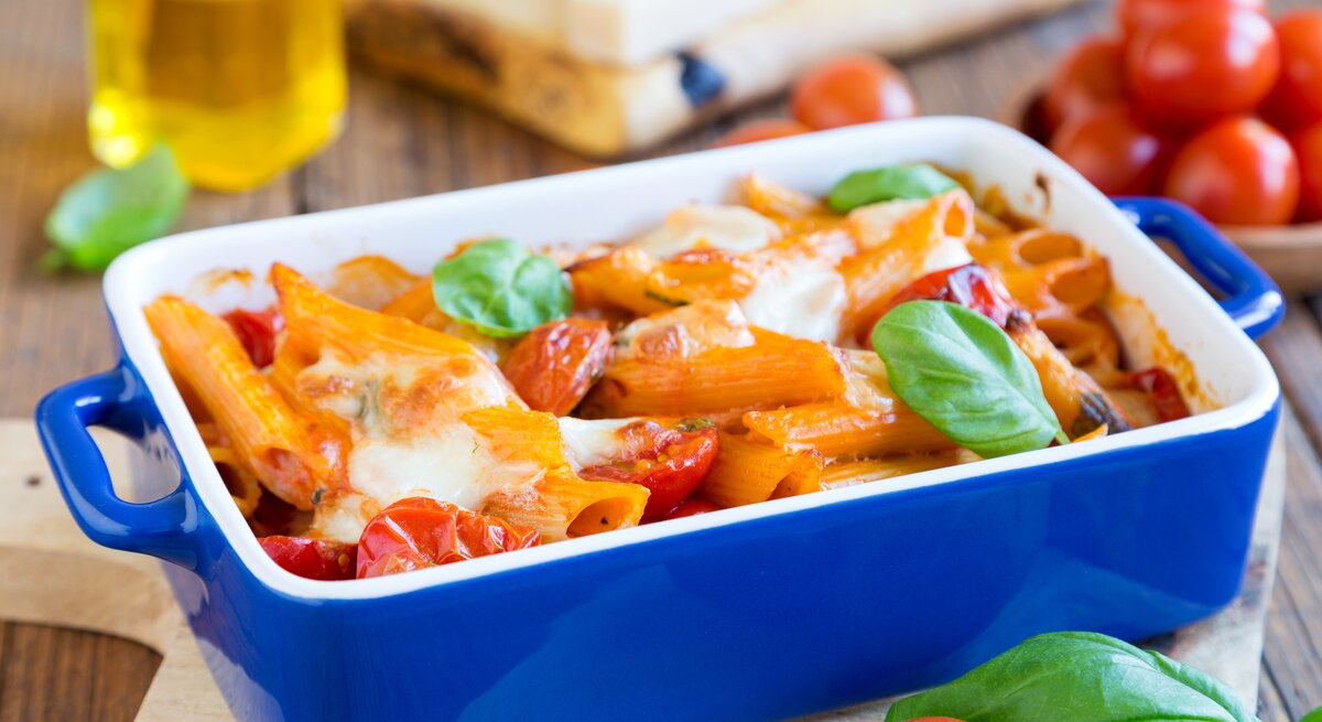 blaue Auflaufform gefüllt mit Tomate-Mozzarella-Auflauf. 