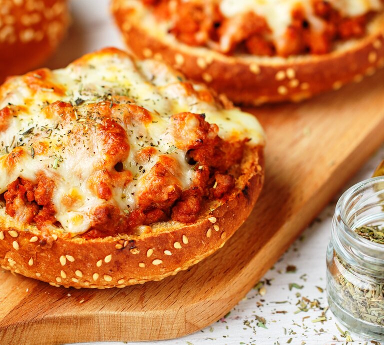 Pizzabrötchen mit Hackfleisch und Käse auf Holzbrett.  | © AdobeStock/ la_vanda