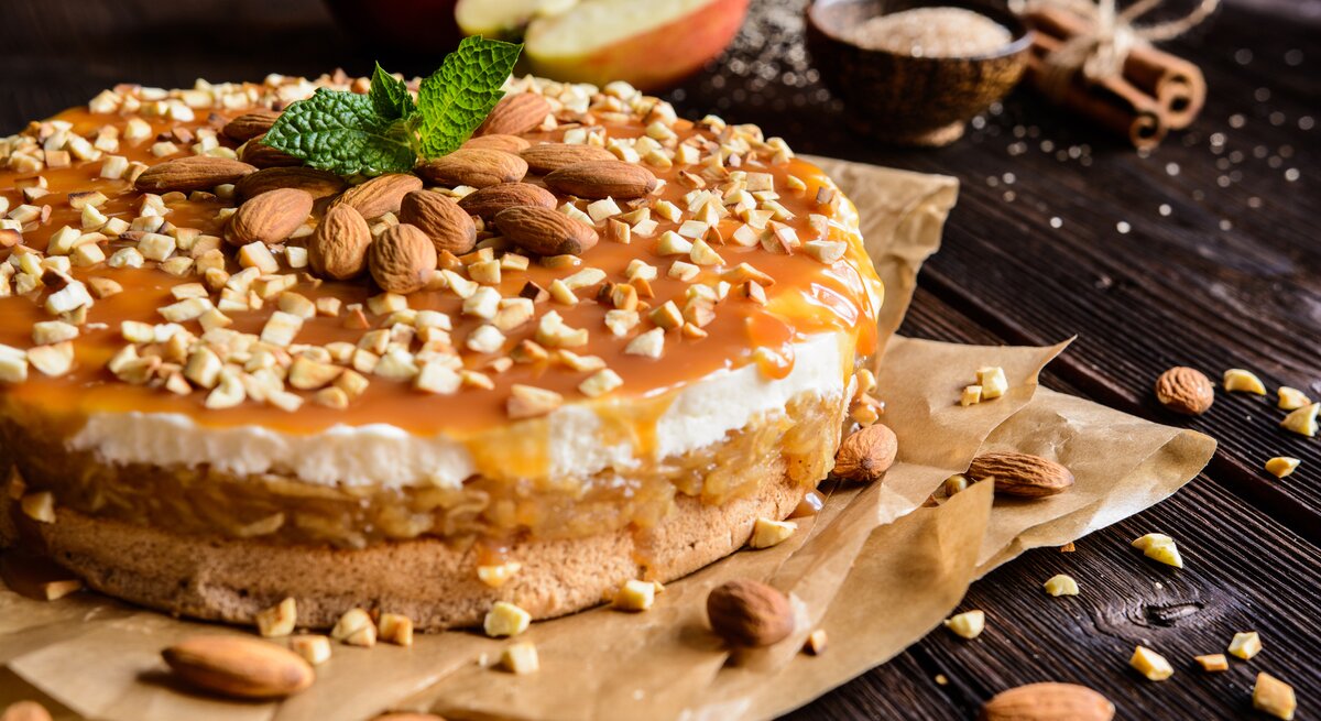 Seitenansicht eines geschichteten, runden Kuchens mit Apfel und Karamellsoße. 