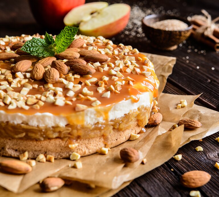 Seitenansicht eines geschichteten, runden Kuchens mit Apfel und Karamellsoße.  | © iStock.com/NoirChocolate