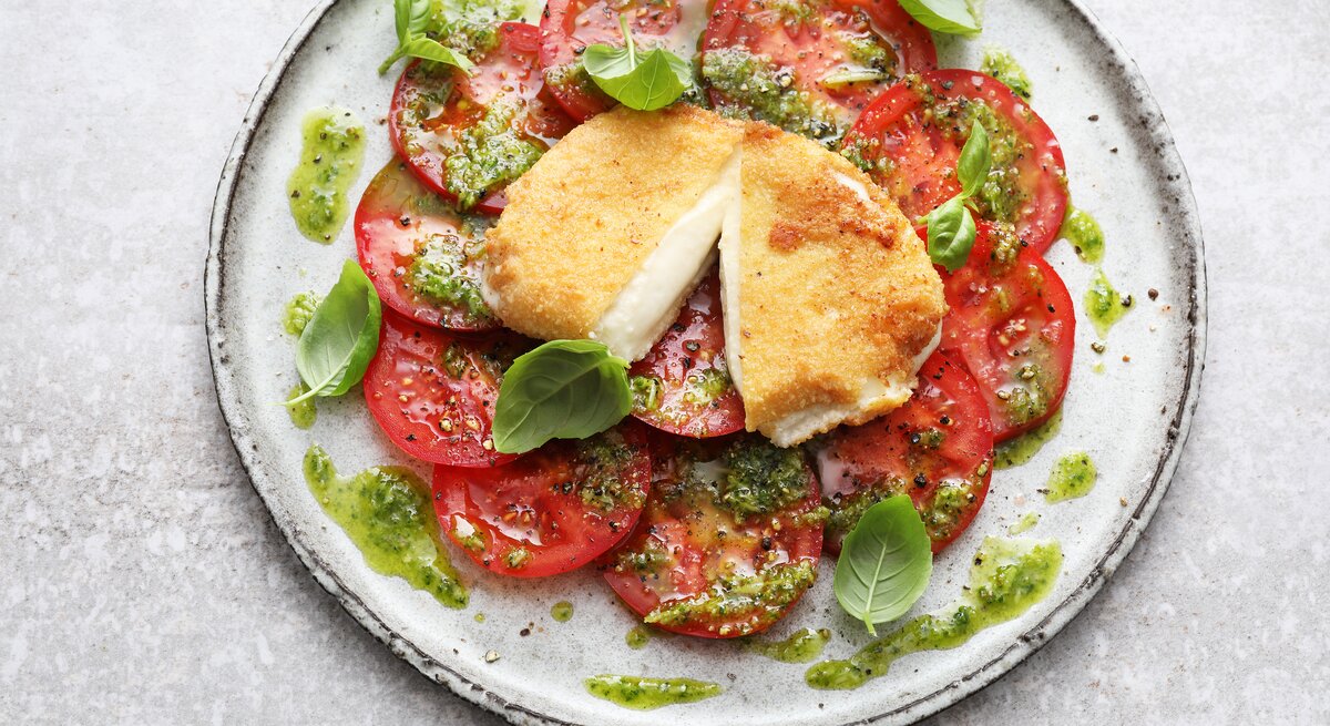 Draufsicht auf einen Teller mit Tomatenscheiben und gebackenem Mozzarella.