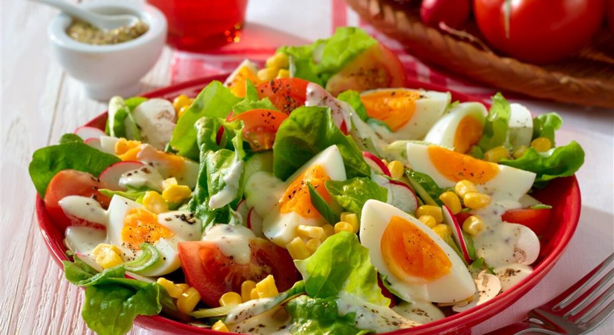 Sommersalat mit Joghurt-Dressing gekochten Eiern Mais und Tomaten /  runder Teller / Nahaufnahme / leichte Draufsicht | © Matthias Liebich