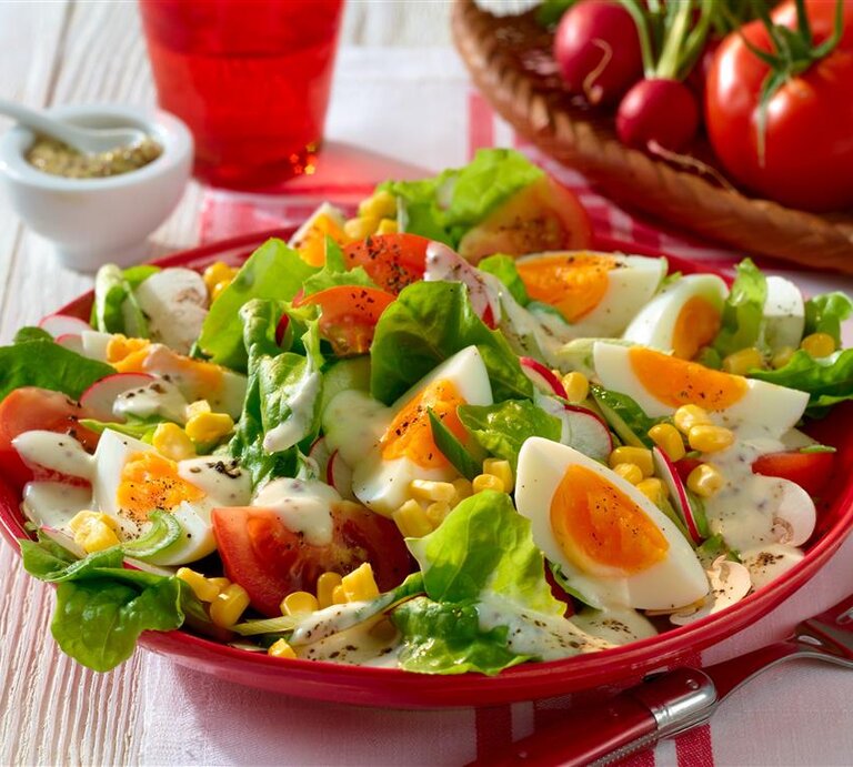 Sommersalat mit Joghurt-Dressing gekochten Eiern Mais und Tomaten /  runder Teller / Nahaufnahme / leichte Draufsicht | © Matthias Liebich