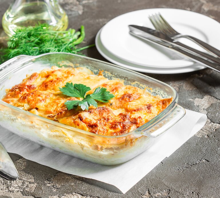 Durchsichtige Auflaufform gefüllt mit Kartoffelauflauf, überbacken mit krosser Käsekruste. | © iStock/ aliona_sipovich