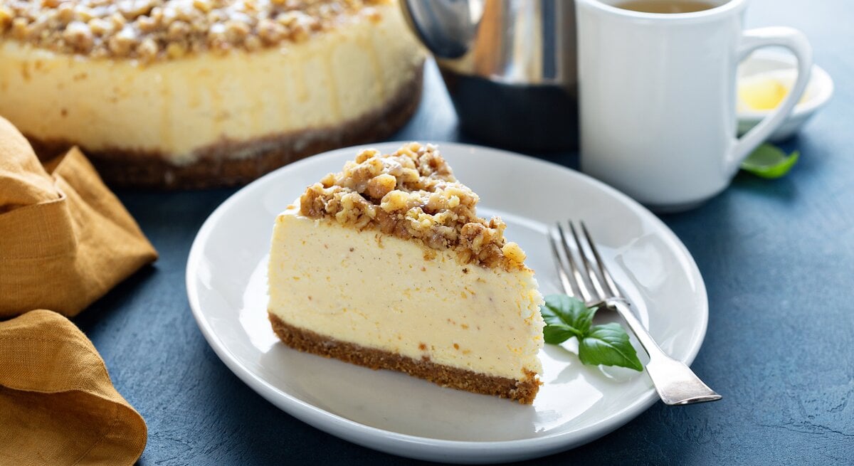 Ein angeschnittenes Spekulatius-Käsekuchen mit Streuseln auf einem weißen Teller. 