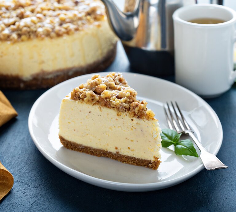 Ein angeschnittenes Spekulatius-Käsekuchen mit Streuseln auf einem weißen Teller.  | © iStock.com/VeselovaElena