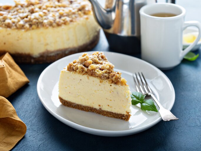 Ein angeschnittenes Spekulatius-Käsekuchen mit Streuseln auf einem weißen Teller.  | © iStock.com/VeselovaElena