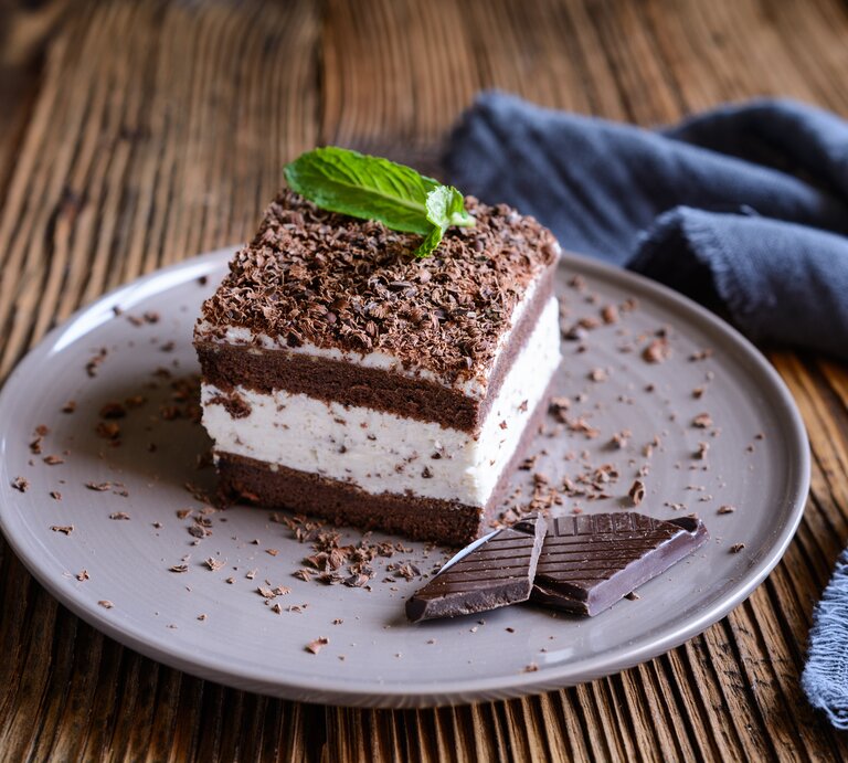 Seitliche Ansicht eines Kuchens mit Sahnefüllung auf Holztisch. | © iStock.com/NoirChocolate