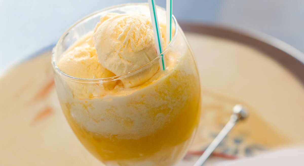 Ein Glas mit einer Kugel Vanilleeis in Orangensaft. 