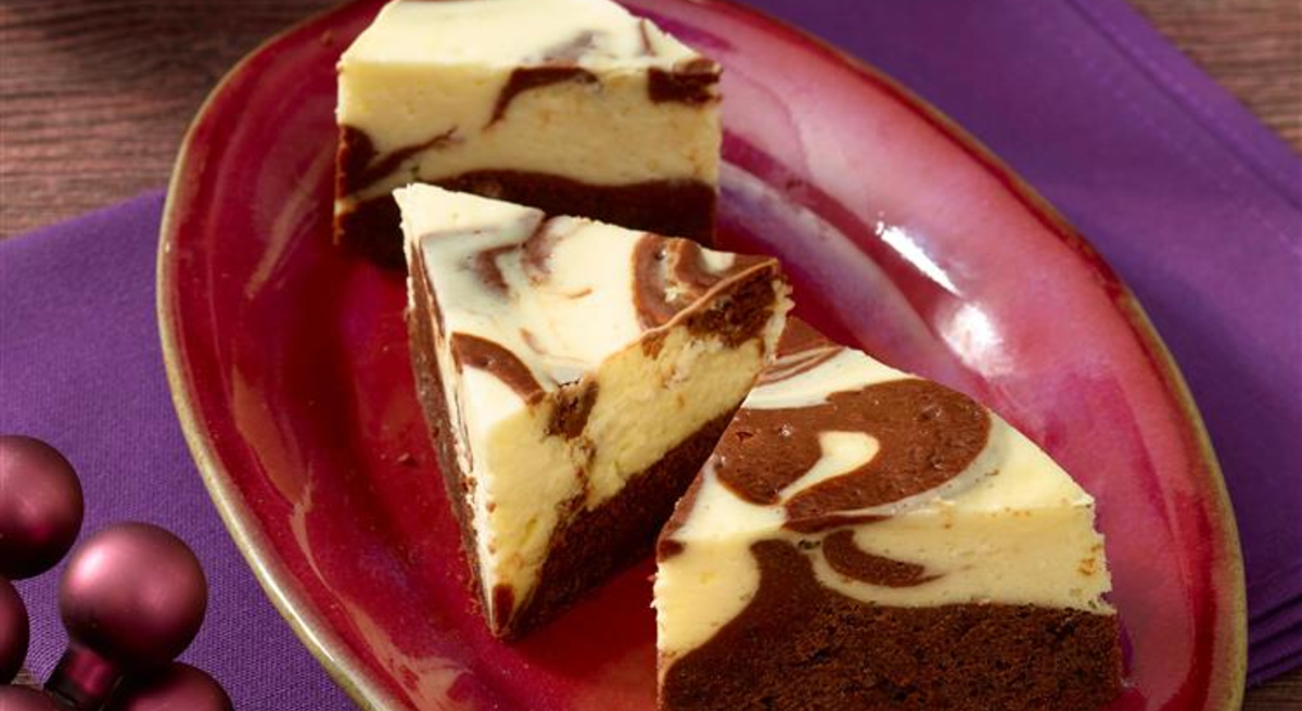 Käsekuchen-Ecken auf einem roten Teller auf einem violetten Geschirrtuch. 