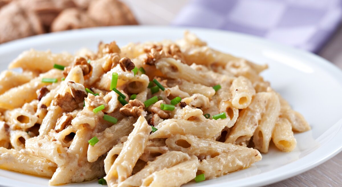 Penne in cremiger Walnusssoße auf weißem Teller. 