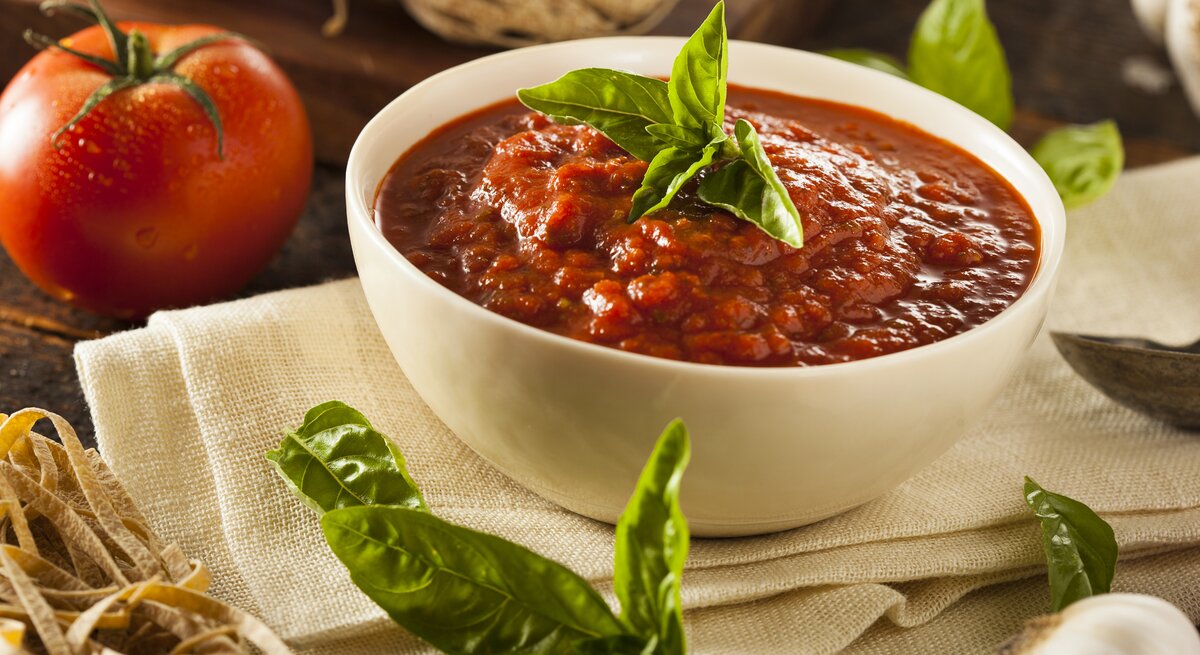Tomatensoße in weißer Schale in mediterranem Ambiente. 