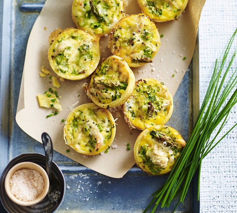Die Miniquiches mit Hähnchen und Spargel auf einem Blech und weißen Tisch. Alles direkt von oben fotografiert. | © StockFood / Bauer Syndication