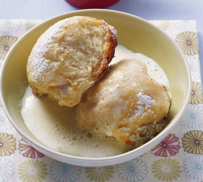 Zwei Dampfnudeln mit Vanillesoße in einer hohen, runden Schale aus Porzellan / Untergrund quadratische papierserviette auf glattem Boden | © StockFood/Eising Studio - Food Photo & Video