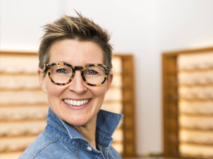 Frau mit kurzen, blonden Haaren trägt eine schwarze Brille und lächelt. Sie hat eine Kurzhaarfrisur für dünnes Haar. | © imago/blickwinkel