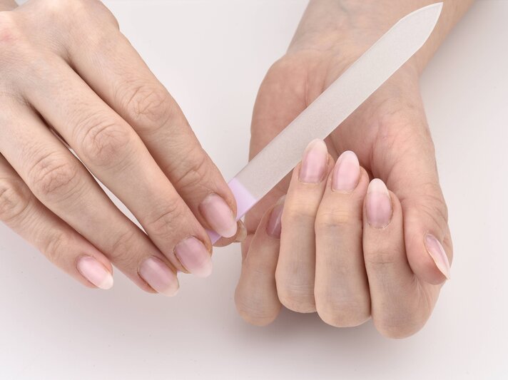 Nahaufnahme von Händen, die eine Nagelfeile benutzen. Die Nägel sind natürlich und gut gepflegt, und die Person feilt sanft an den Nägeln. | © imago/Michael Weber