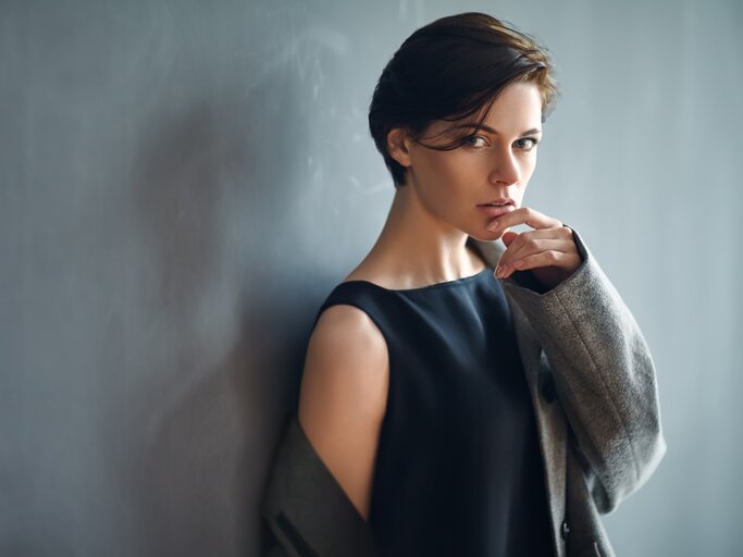 Junge, dunkelhaarige Frau mit Kurzhaarfrisur trägt ein schwarzes Kleid und hat einen verführerischen Blick.  | © istock/Viktor_Gladkov