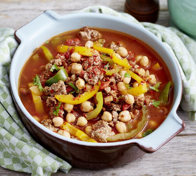 Orientalischer Kichererbseneintopf mit Paprika, Chili, Hackfleisch und Kichererbsen in einer hellen Form auf einem Holztisch | © Eat Club / Isabell Triemer 