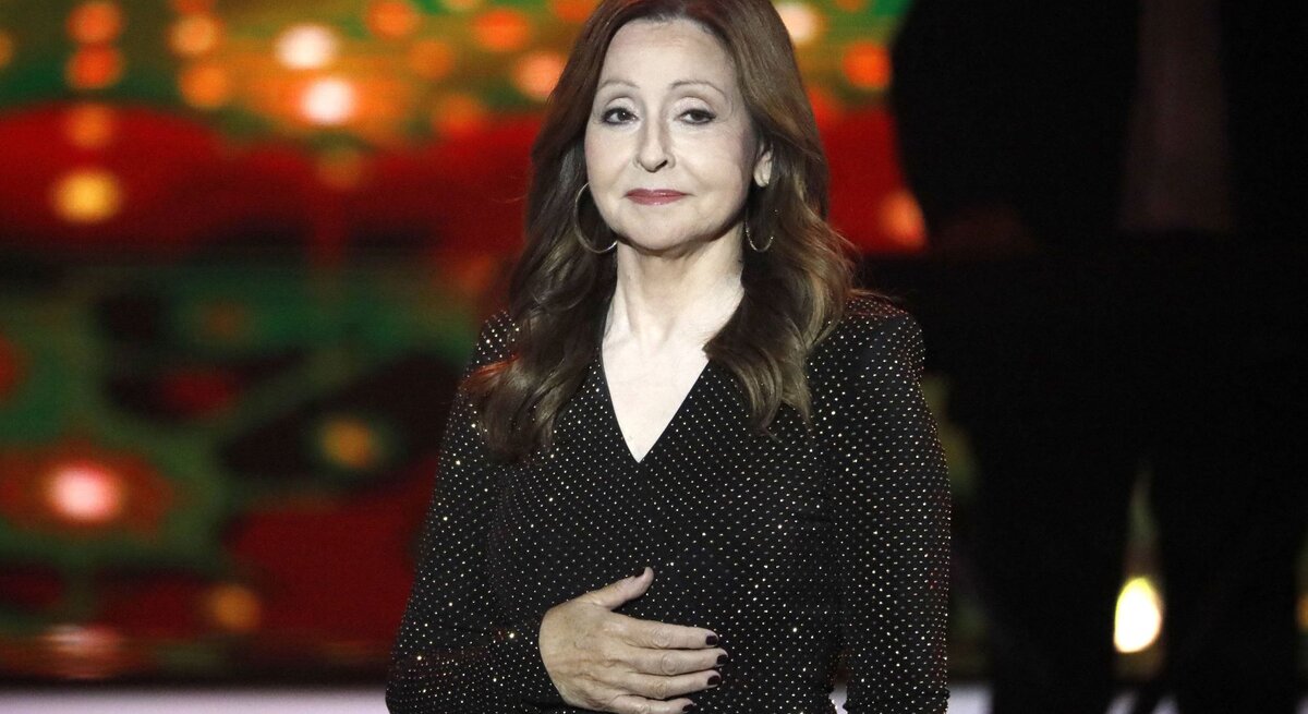 Sängerin Vicky Leandros in glitzernder Abendrobe auf einer Bühne, sie macht einen gerührten Eindruck