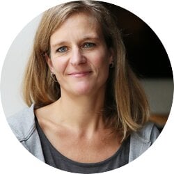 Das Bild zeigt eine Frau mit freundlichem Lächeln, die direkt in die Kamera blickt. Sie hat mittellanges blondes Haar, blaue Augen und trägt ein graues T-Shirt mit einer offenen grauen Jacke. Der Hintergrund ist schlicht und unauffällig, was den Fokus auf die Frau lenkt. Ihr Ausdruck wirkt offen und zugänglich. | © BILD der FRAU