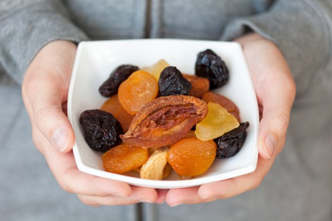 Frau hält Schale mit Trockenobst in der Hand. | © iStock/Professor25