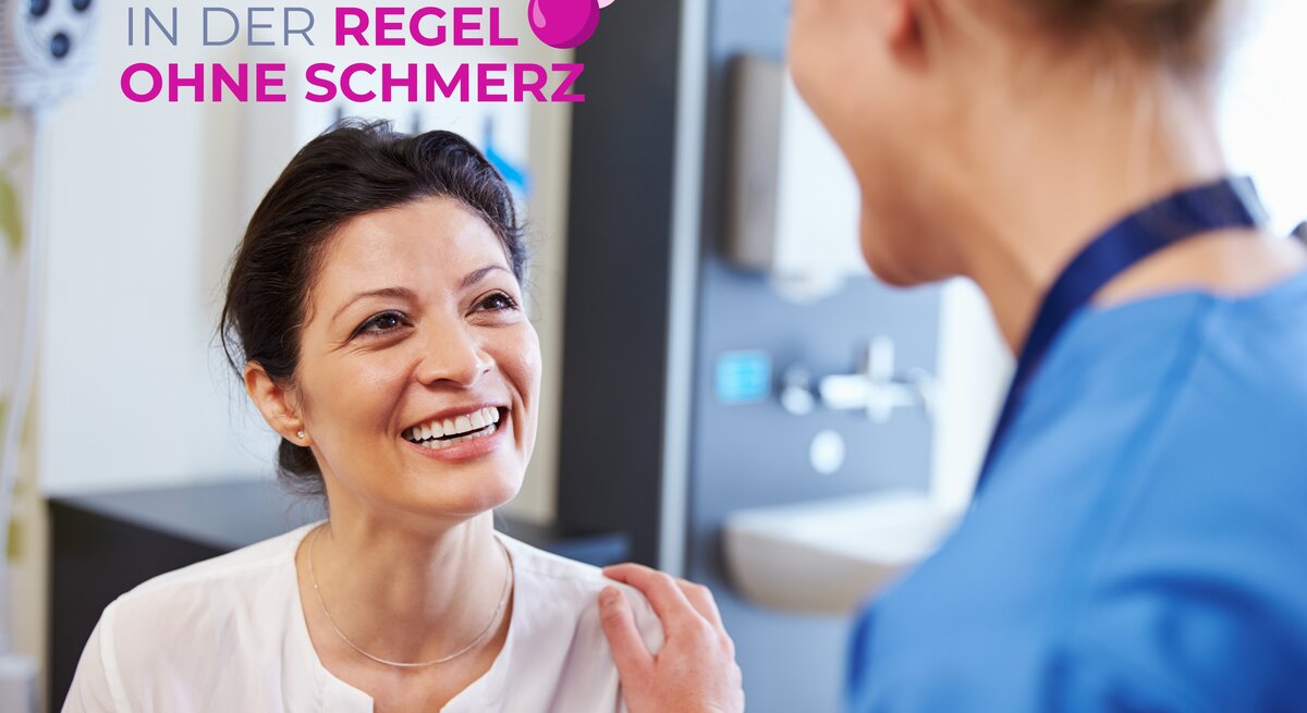 Frau sitzt gegebenüber von Ärztin, die sie vertrauensvoll an der Schulter anfässt.