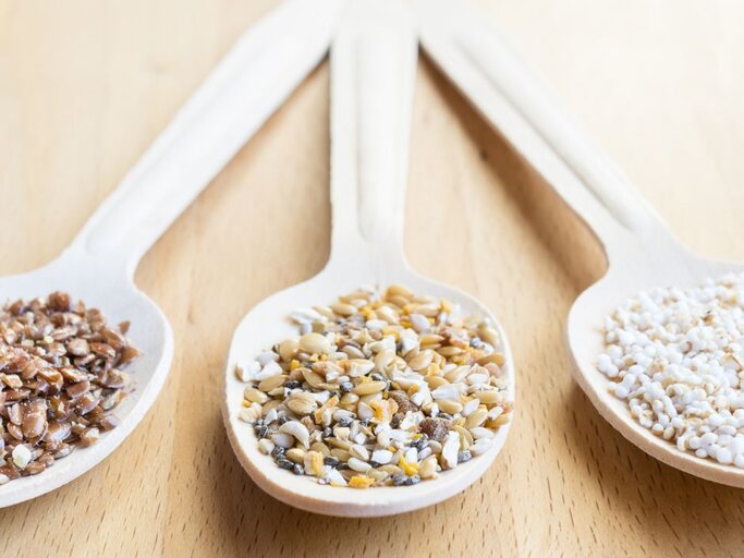 Drei Holzlöffel mit Leinsamenmischung, Amaranth und gepufftem Getreide. | © Adobe Stock/ Angela Rohde
