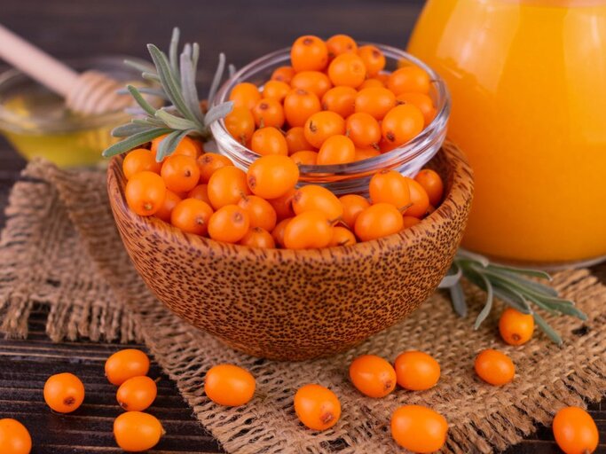 Schale mit frischen Sanddornbeeren und Sanddornsaft – eines der vitamin-C-reichsten Lebensmittel, perfekt für Immunsystem und Haut. | © Getty Images/ Olivka888 via Canva.com
