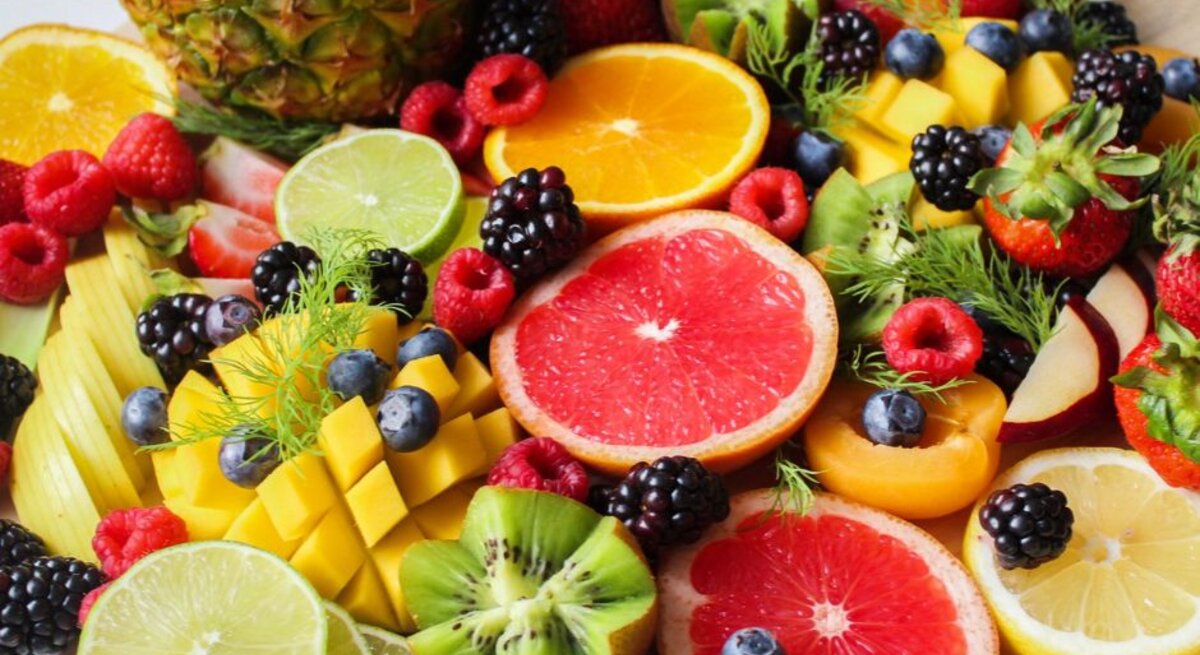Bunt angerichtete Obstplatte mit frischen Früchten wie Grapefruit, Orange, Kiwi, Mango, Beeren, Erdbeeren, Limetten und Ananas; gesunde, farbenfrohe Vitaminquelle für Ernährung und Fitness.