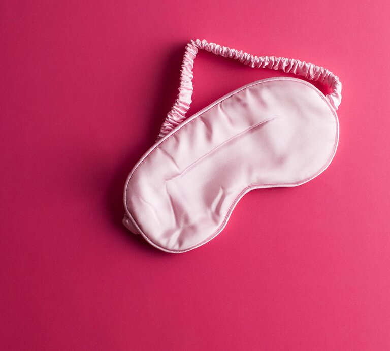 Schlafmaske auf rosa Untergrund. | © Getty Images/ Karl Tapales