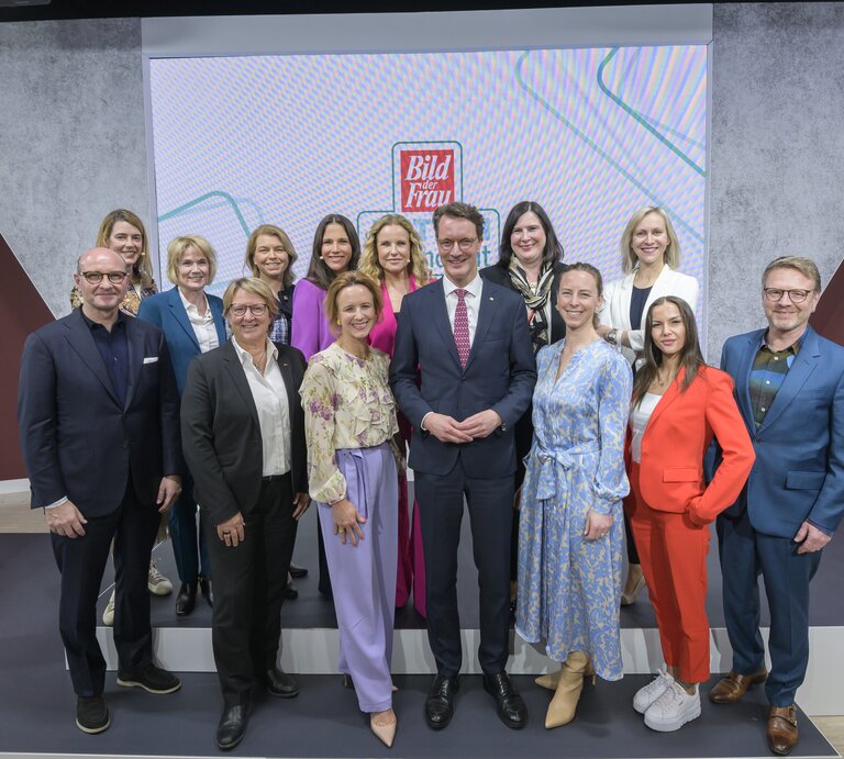 Vierzehn Frauen und zwei Männer in Businesskleidung posieren lächelnd auf einer Bühne vor „Bild der Frau“-Logos. | © Henning Scheffen