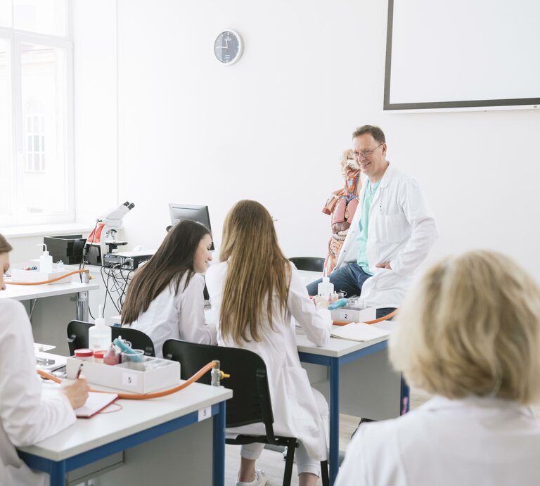 Ein Arzt unterrichtet angehende Ärztinnen in einem Klassenraum. | © dpa