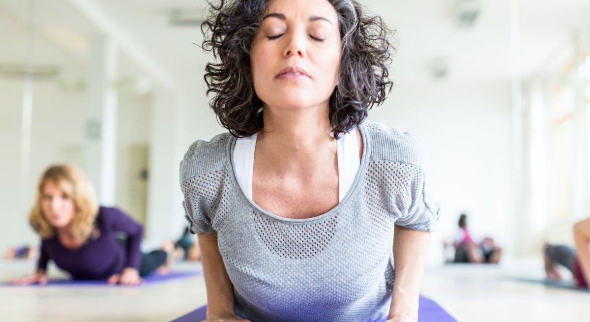 Frau übt in einem Yoga-Studio die Yoga-Übung Kobra aus.