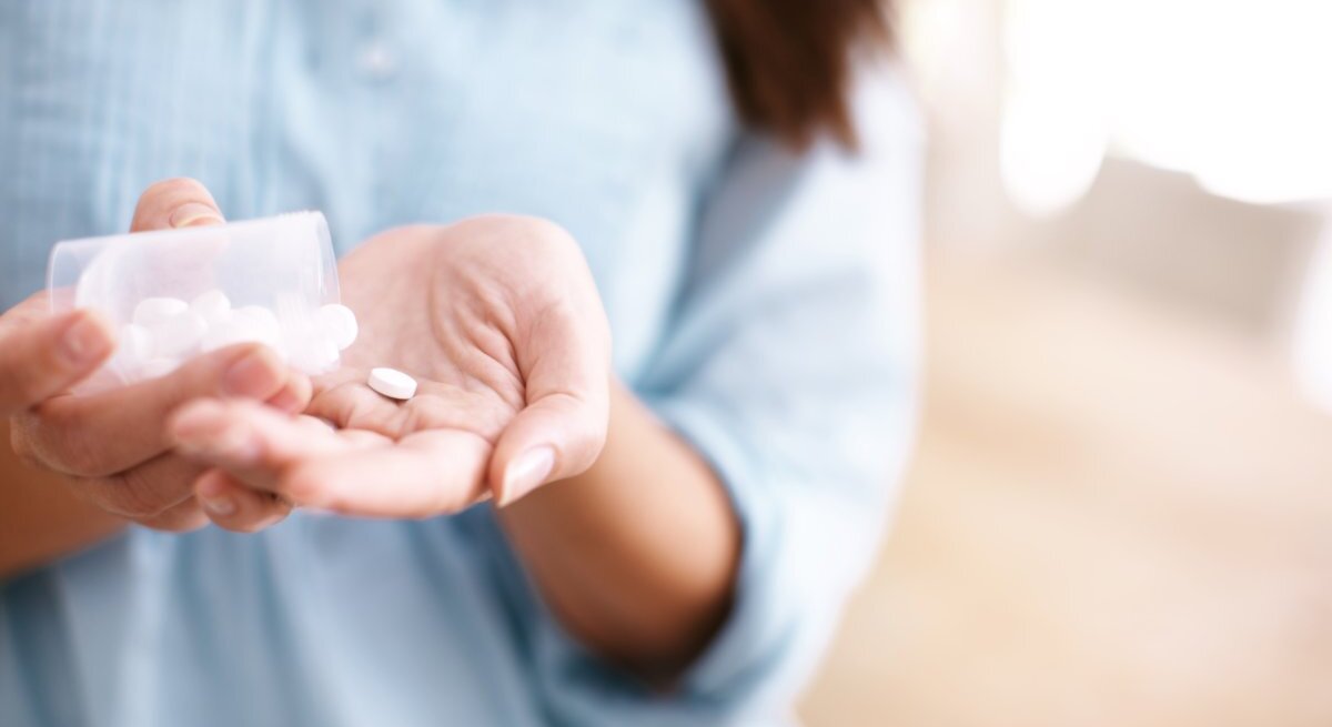 Eine Frau schüttet Tabletten in ihre ausgestreckte Hand