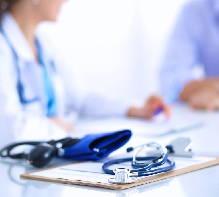 Beratungsgespräch in Arztpraxis, weibliche Ärztin mit blauem Stethoskop spricht mit Patient. | © Shutterstock/sheff