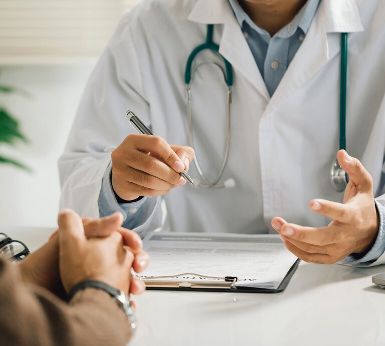 Ein Arzt spricht mit Patient. Gesichter sind nicht zu sehen, dafür gestikulierende Hände und ein Klippboard. | © Adobe Stock/cess609